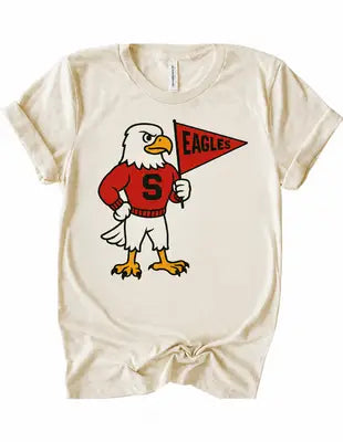 An off-white short-sleeve t-shirt featuring a cartoon bald eagle mascot wearing a red sweater with a large letter 'S' and holding a red pennant that says 'EAGLES'.