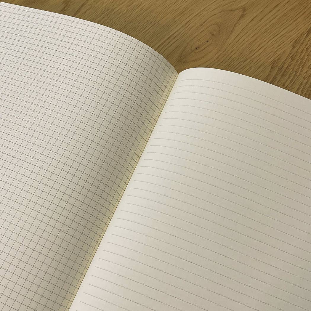 Open notebook with grid and lined pages on a wooden surface