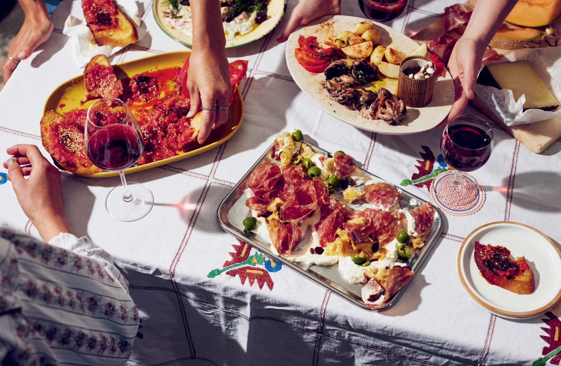 People enjoying a meal with various dishes including flatbreads and wine on a table.
