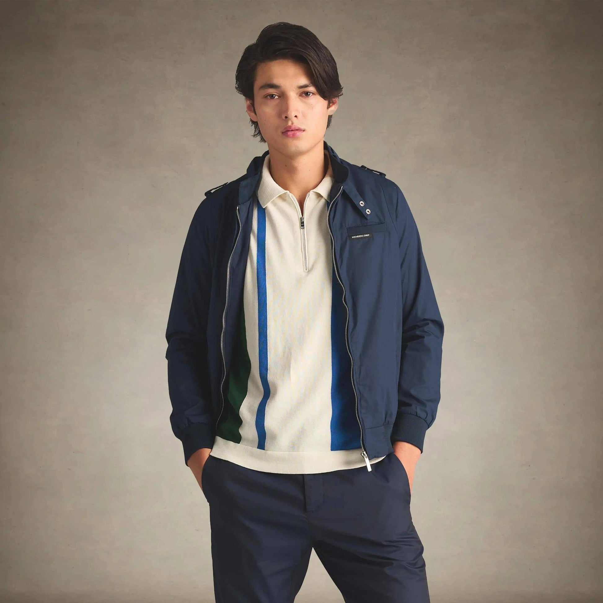 Man wearing a navy jacket over a white shirt with blue accents on a beige background