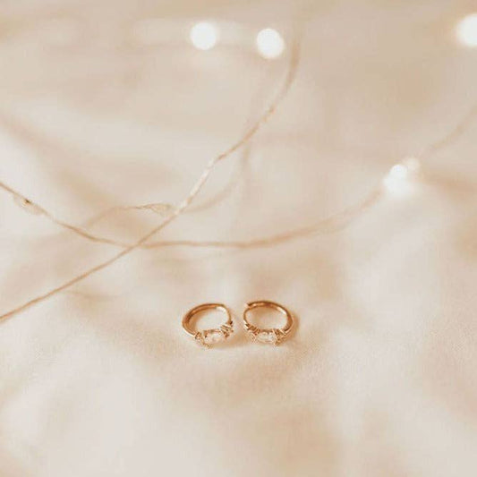 Gold hoop earrings on a beige fabric background