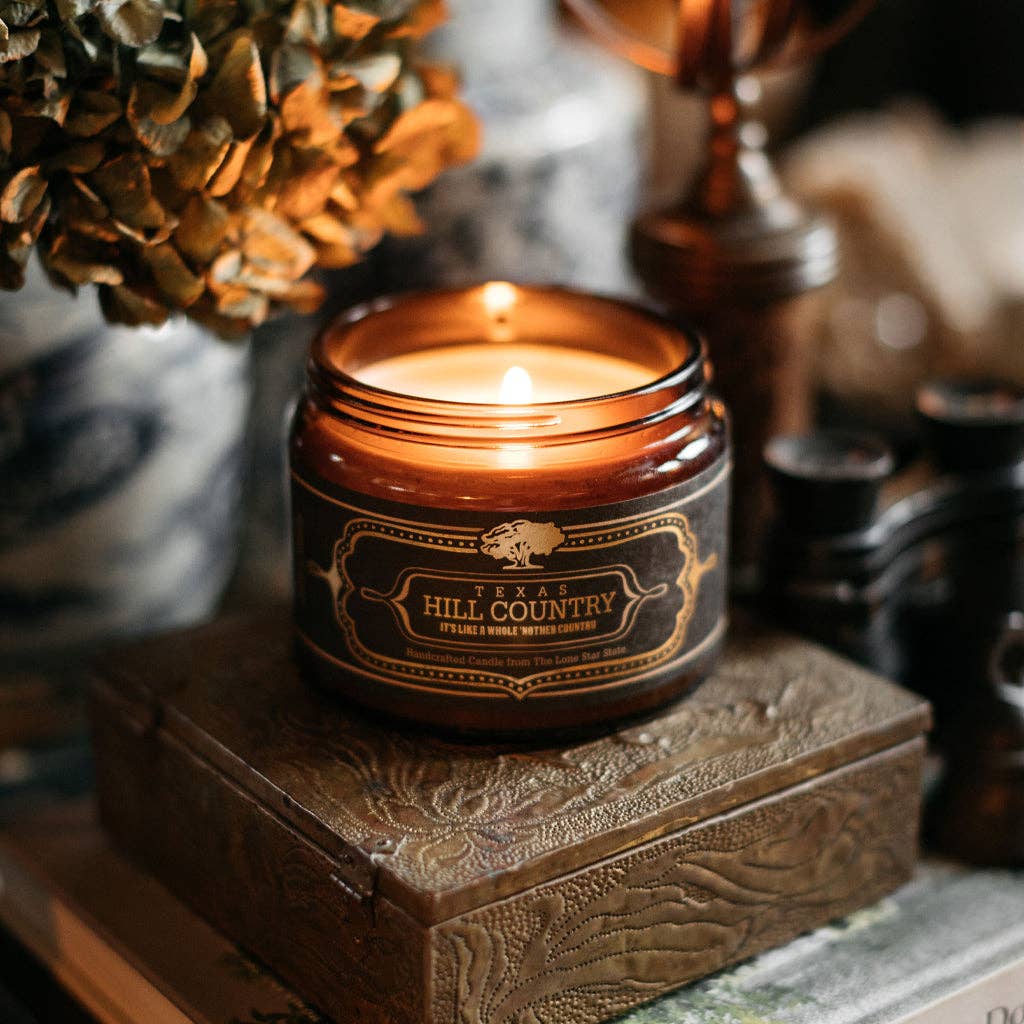 Candle in a amber jar labeled 'Texas Hill Country' on a decorative box with a blurred background
