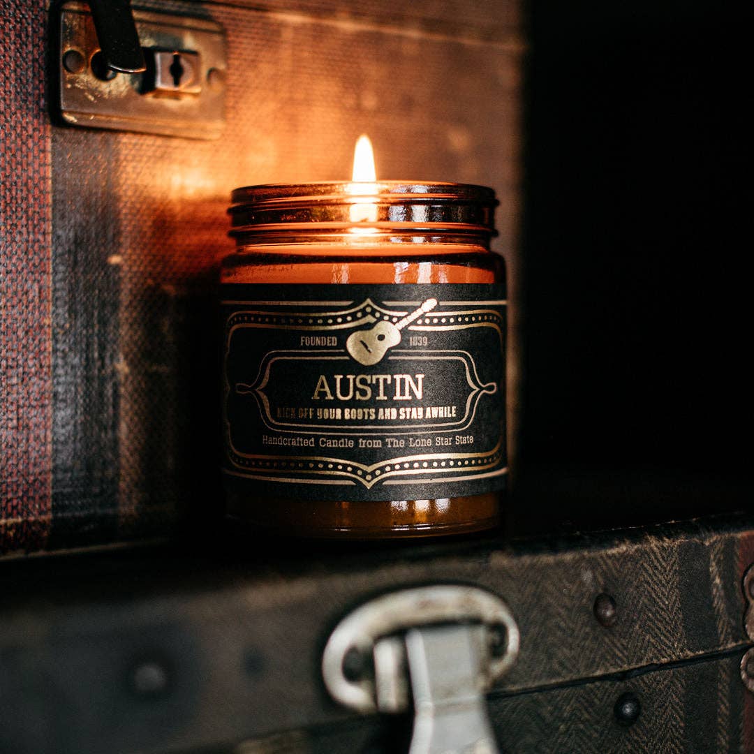Candle in a jar labeled 'Austin' on an old suitcase.