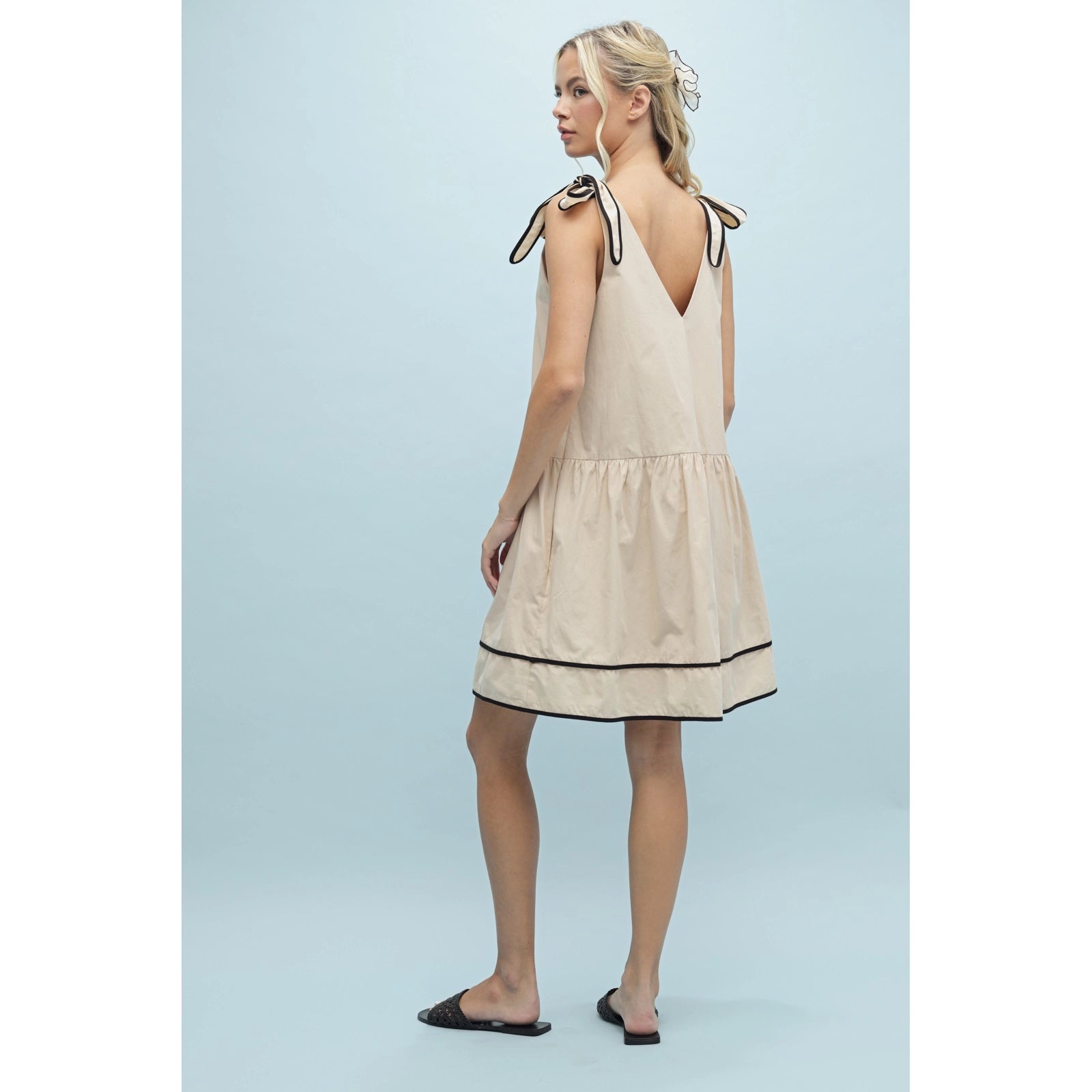 Woman wearing a beige dress with black trim 