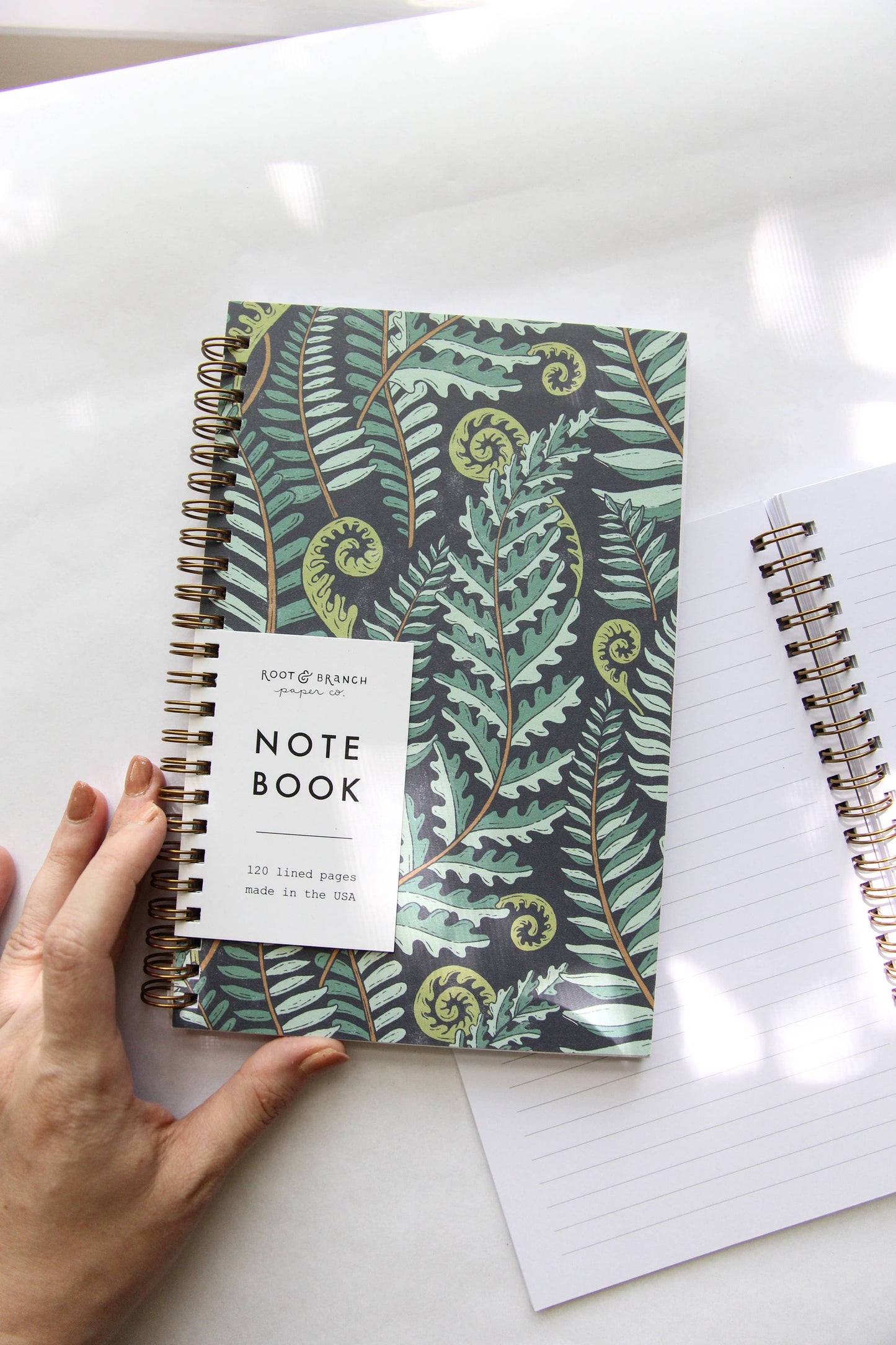 Notebook with fern pattern cover on a white surface