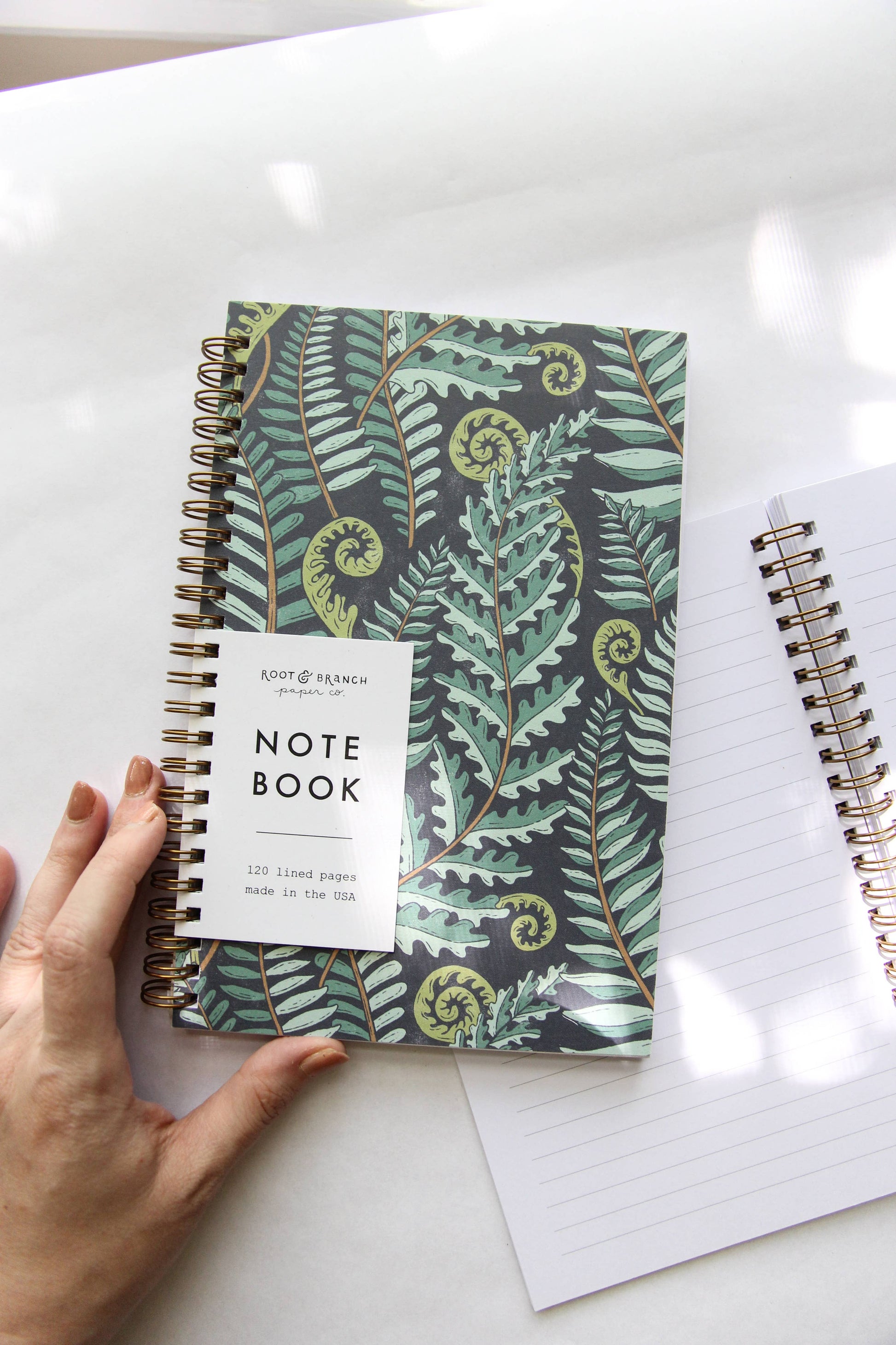 Notebook with fern pattern cover on a white surface