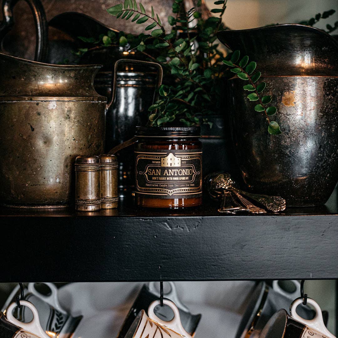 candle that says san antonio on a shelf