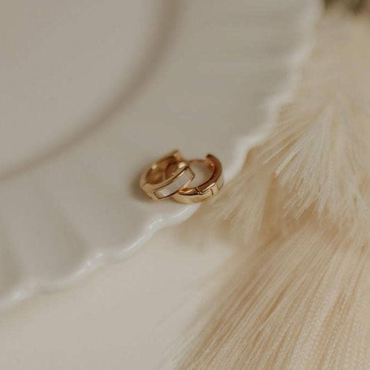 Gold hoop earrings on a textured beige surface