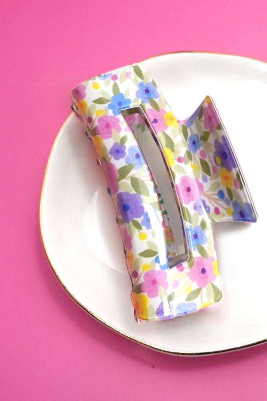 Decorative letter 'H' with a floral pattern on a pink background