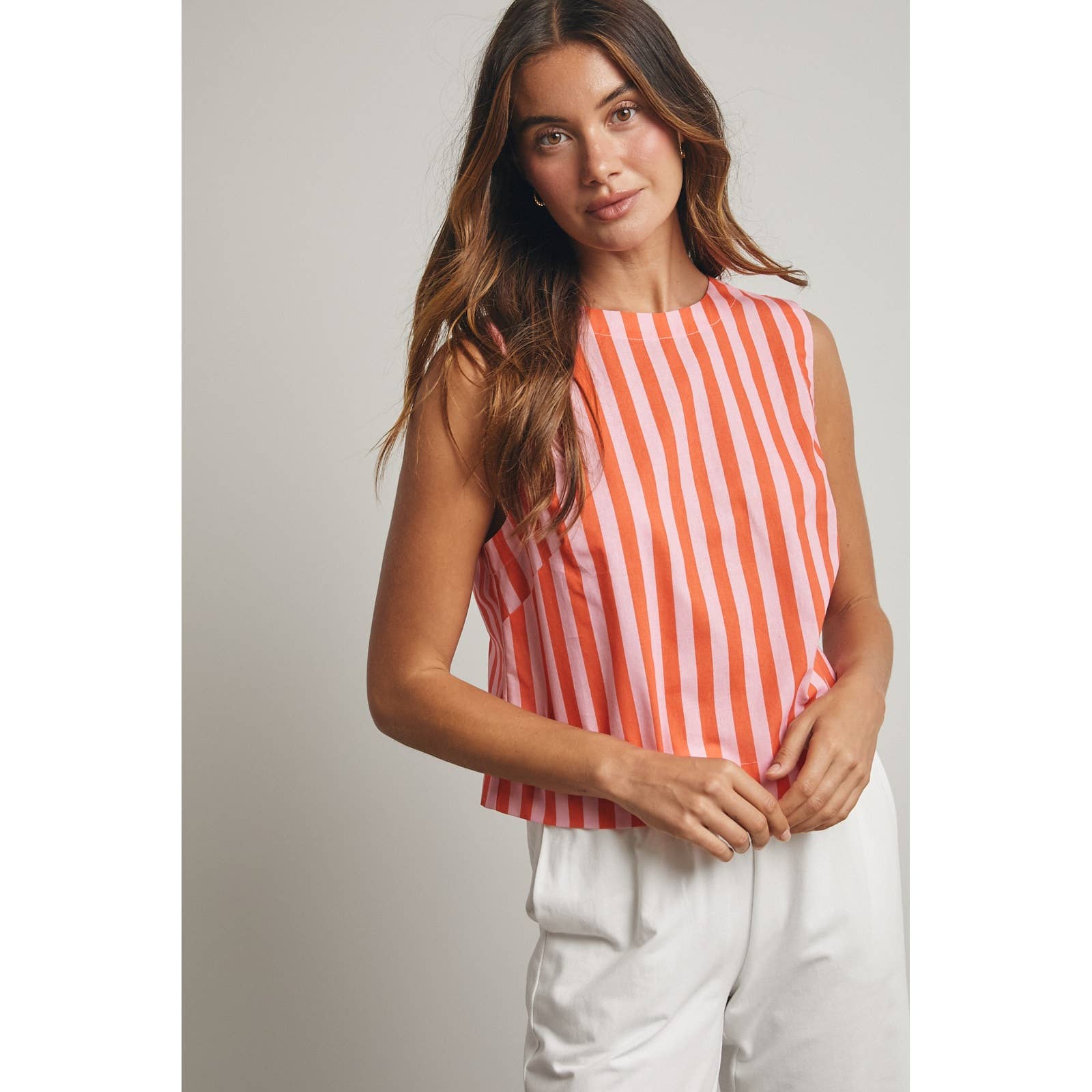 Woman wearing a sleeveless orange and pink striped top 