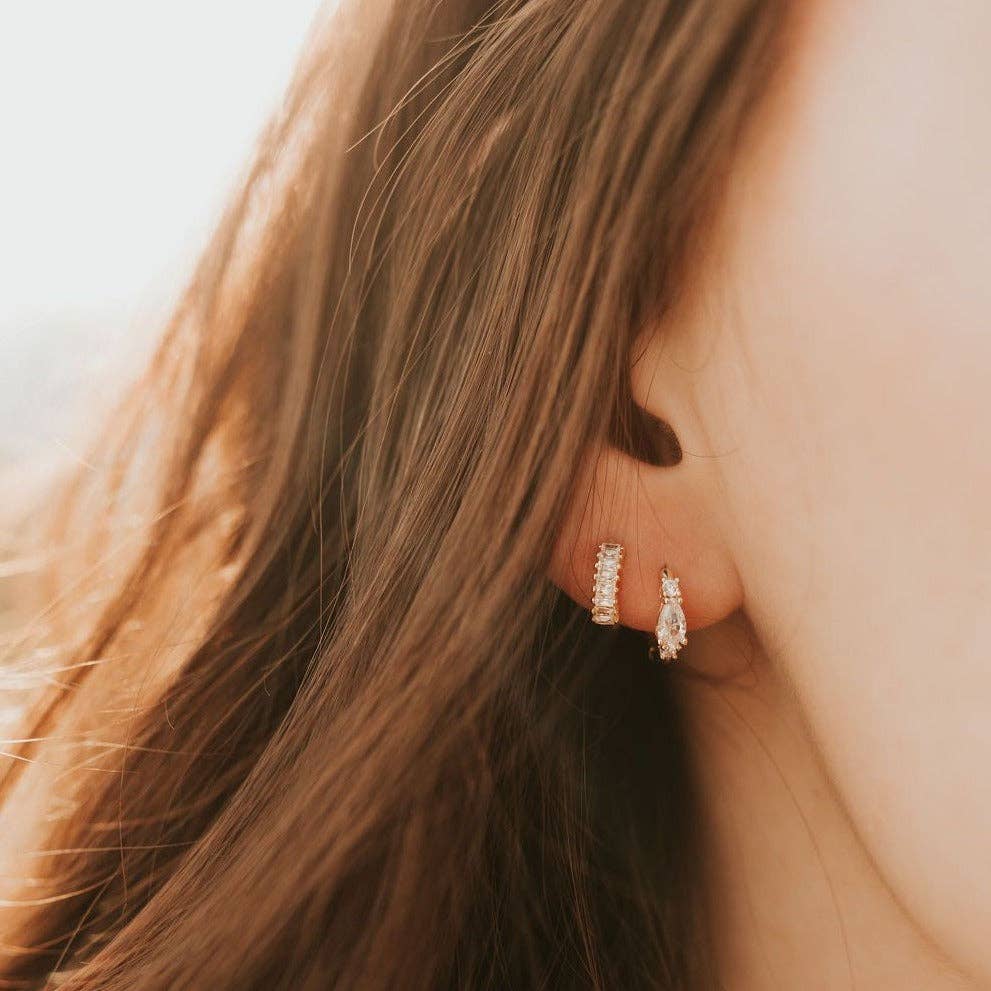 Close-up of a person wearing diamond hoop earrings with soft background