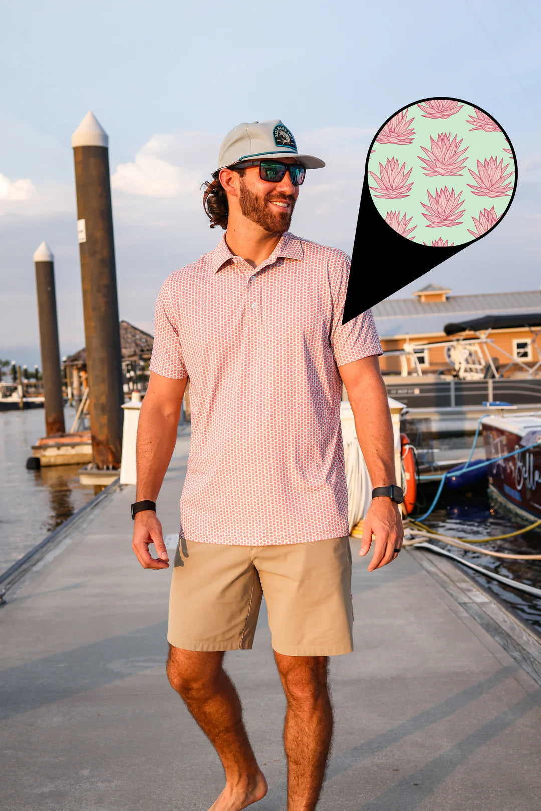Man walking on a dock wearing a pink shirt and beige shorts