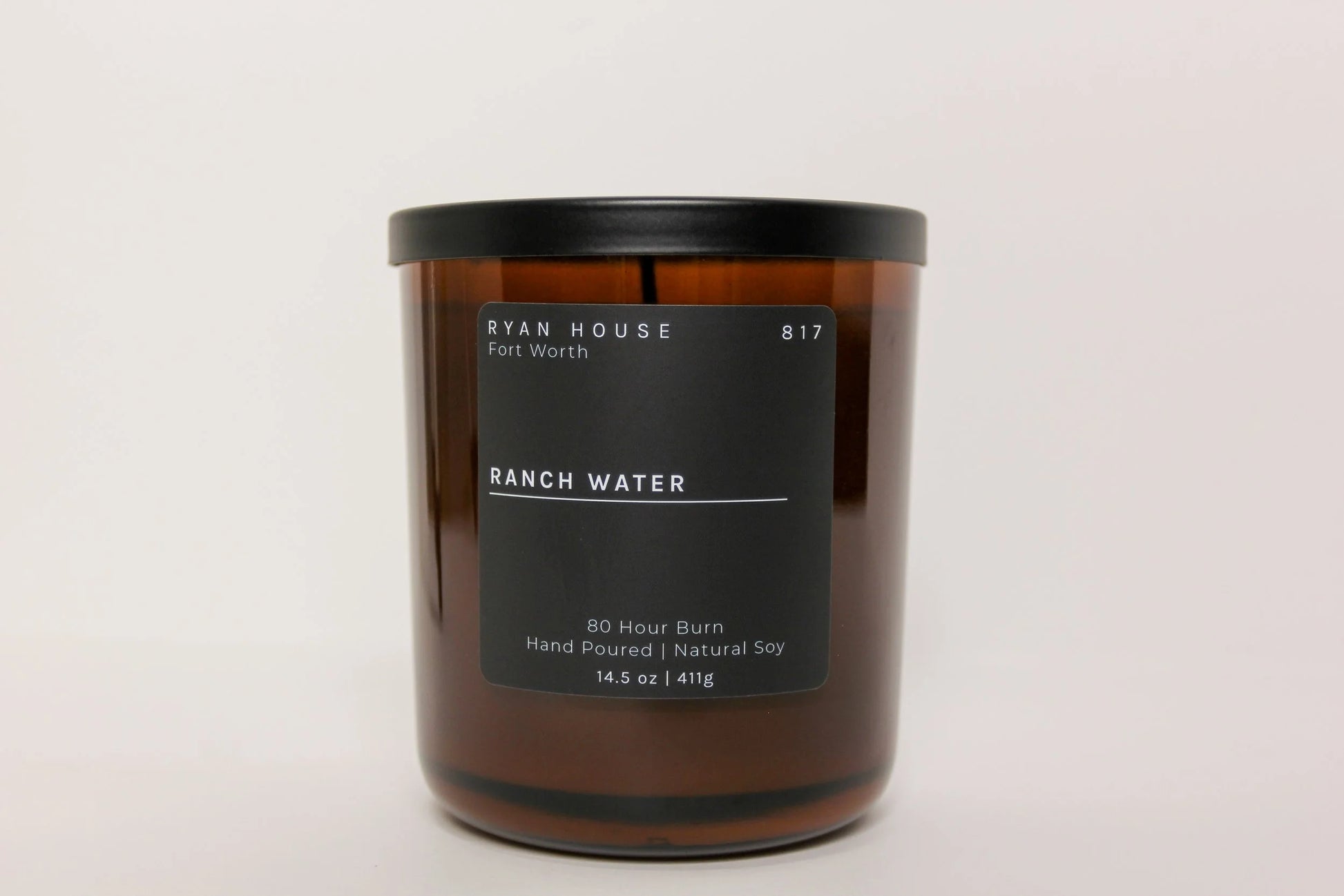 Brown candle with a black label on a white background