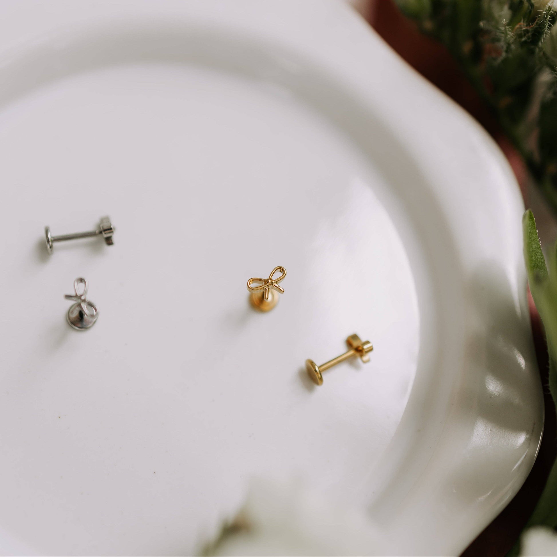 Gold and silver earrings on a white plate with a blurred natural background