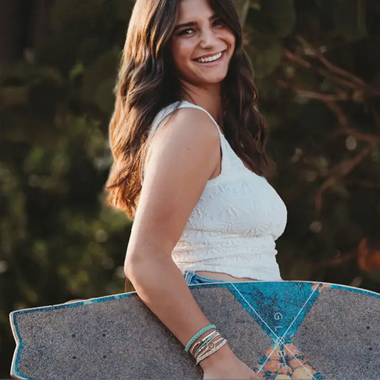 Woman holding a skateboard with a blurred natural background