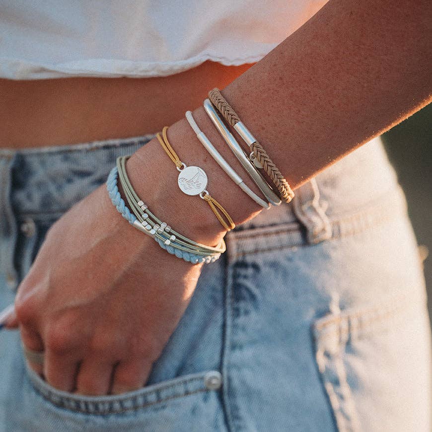 Close-up of a person's wrist wearing multiple bracelets with a blurred background