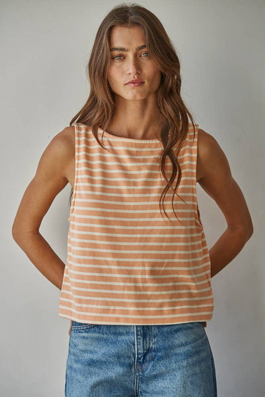 Woman wearing a striped tank top and jeans against a plain background