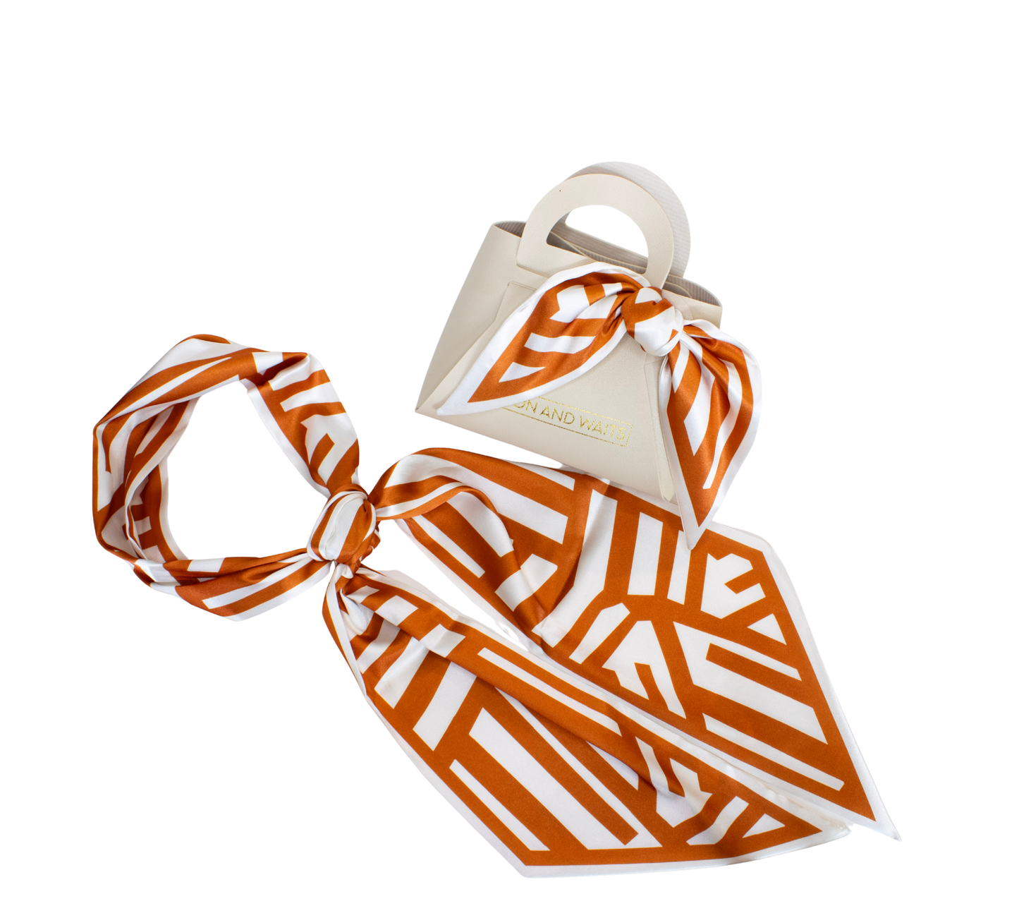 An orange and white geometric patterned silk scarf styled with a cream-colored leather handbag on a solid white background.