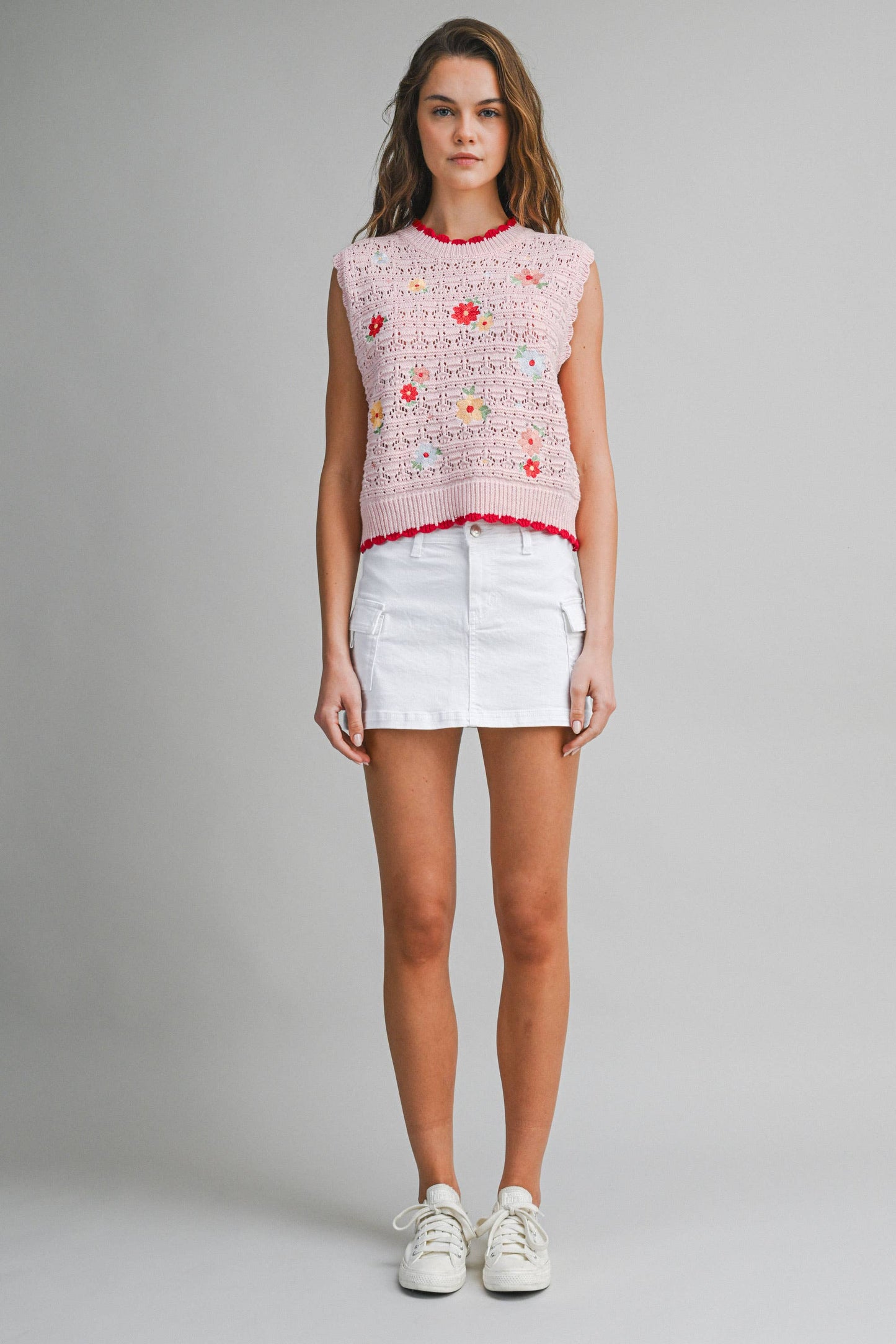 Woman wearing a pink floral sleeveless top and white shorts 