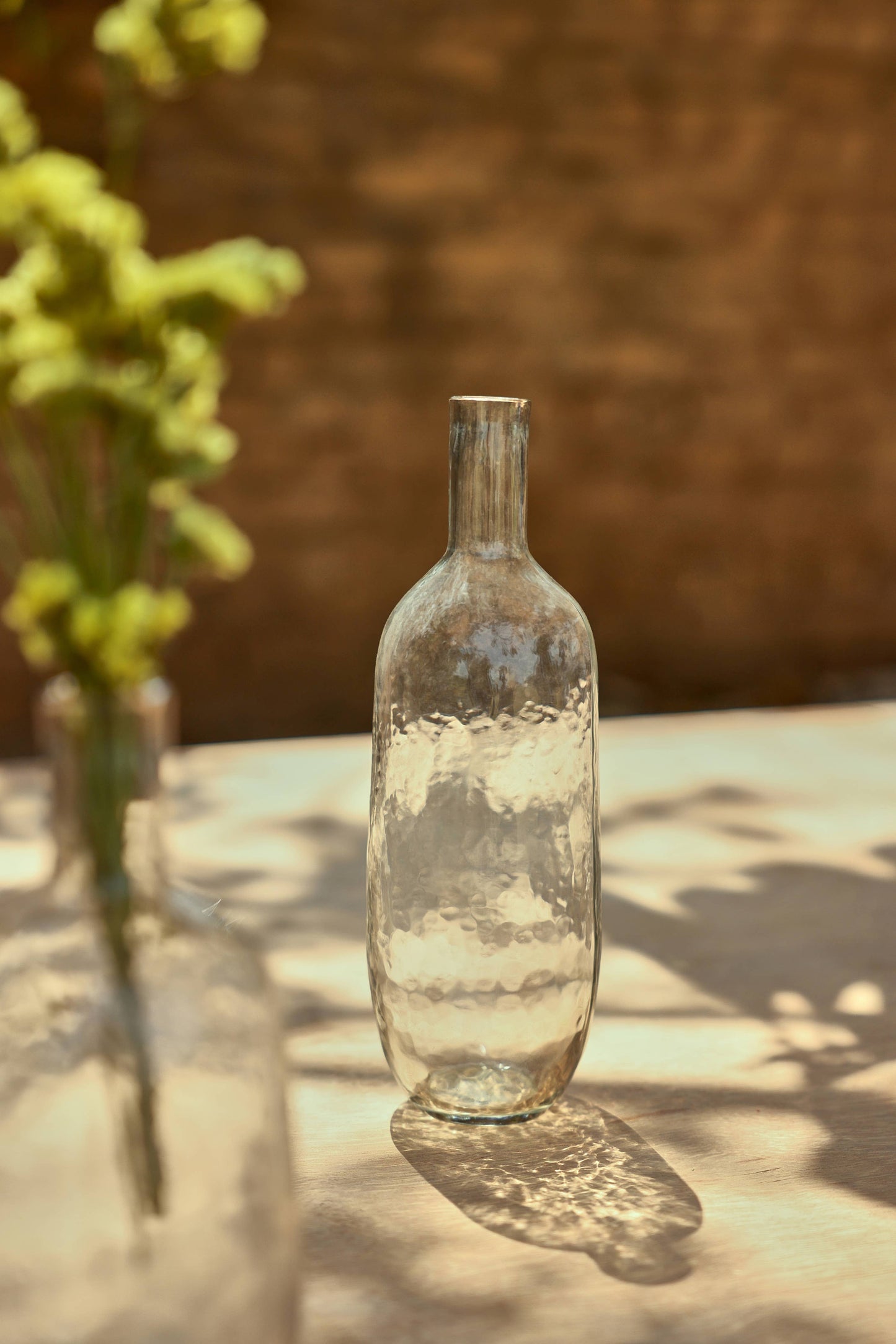 Clear glass bottle on a reflective surface with a blurred natural background