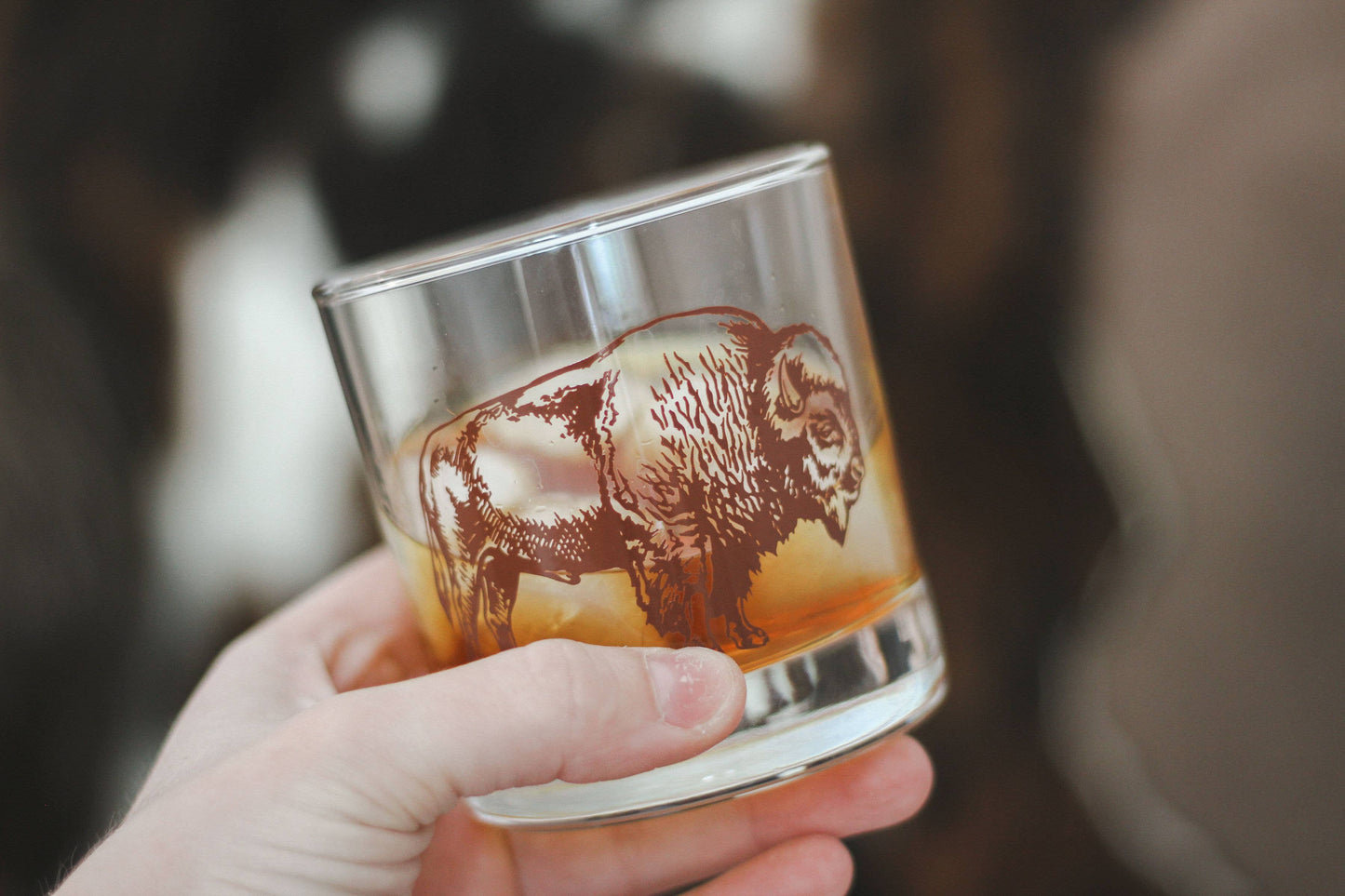 bison on a rocks glass being held by a hand 