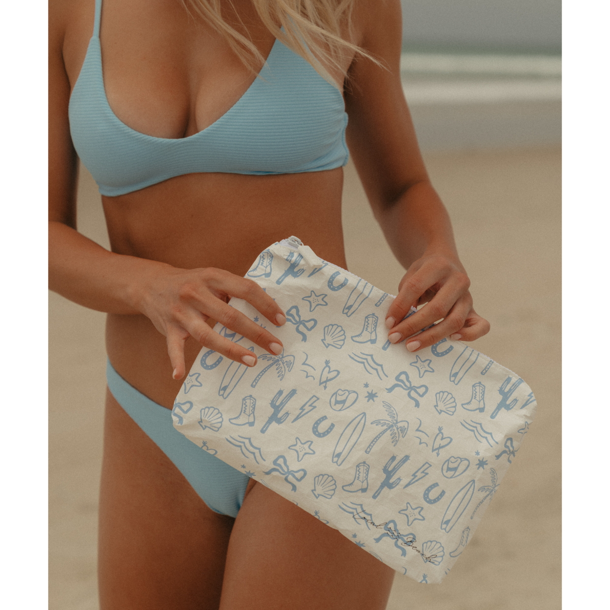 Person holding a beach towel with sea-themed pattern on a beach