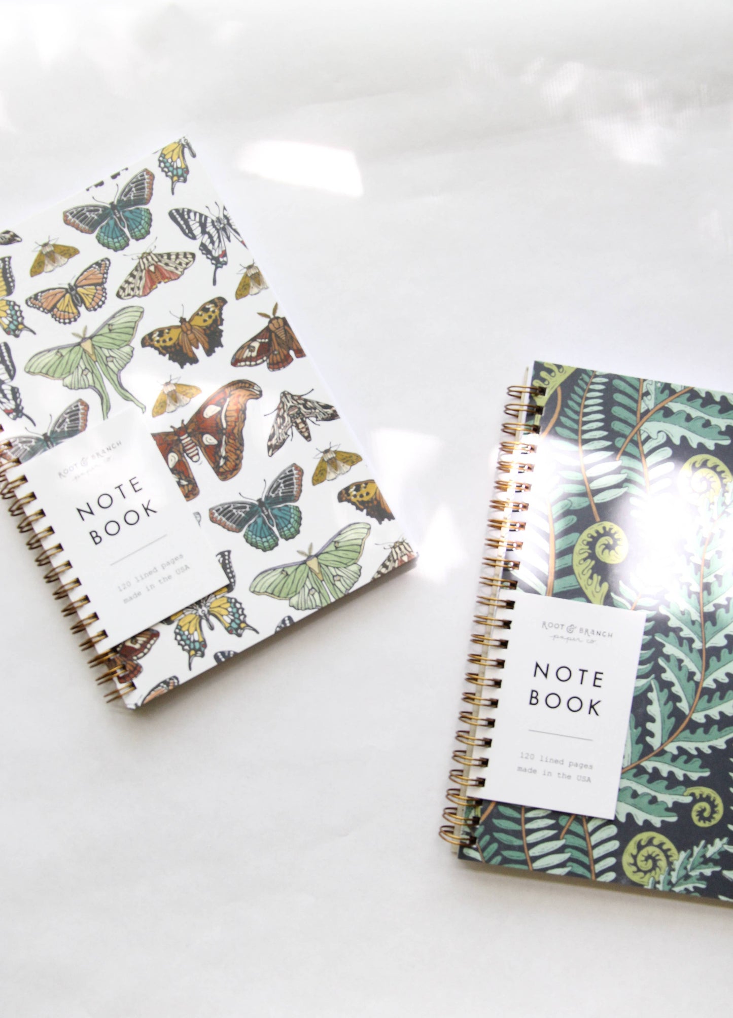 Two notebooks with butterfly and nature-themed covers on a white surface