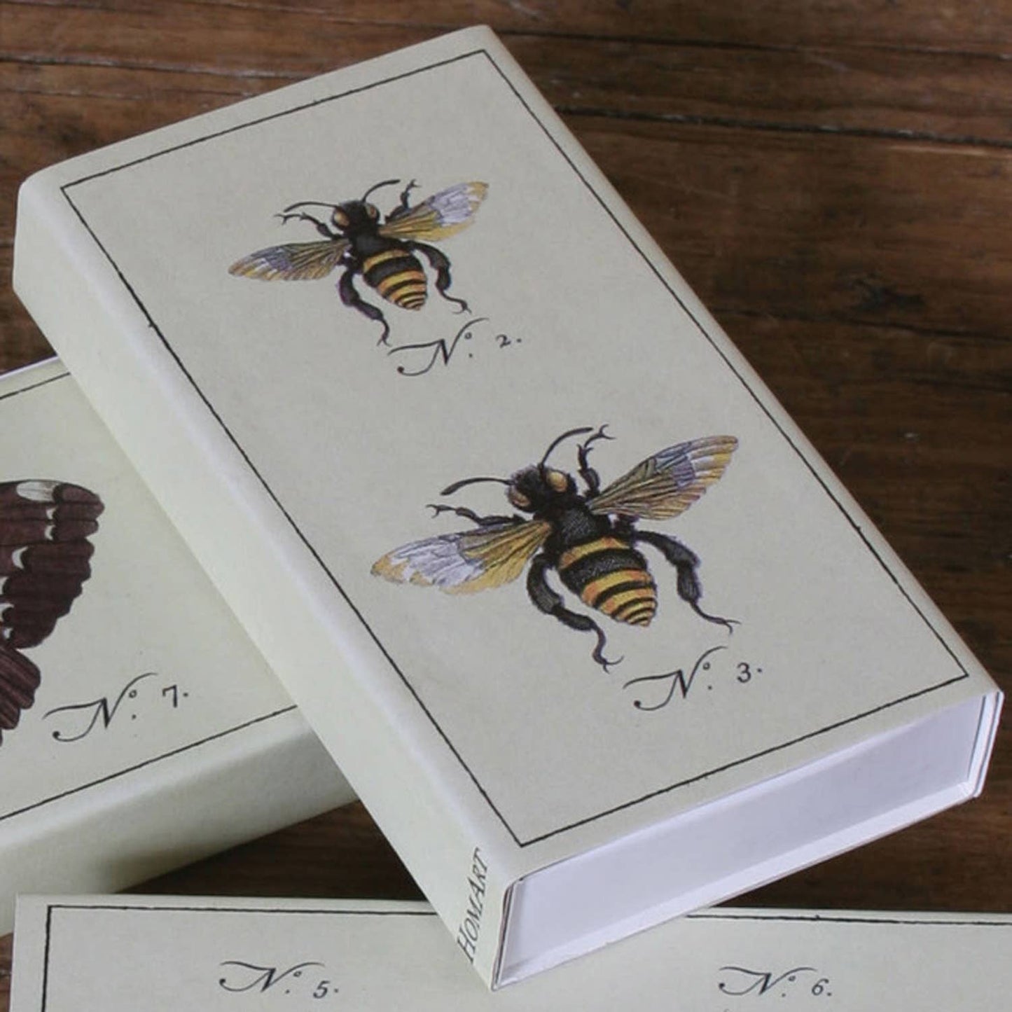Playing card box with bee illustrations on a wooden surface
