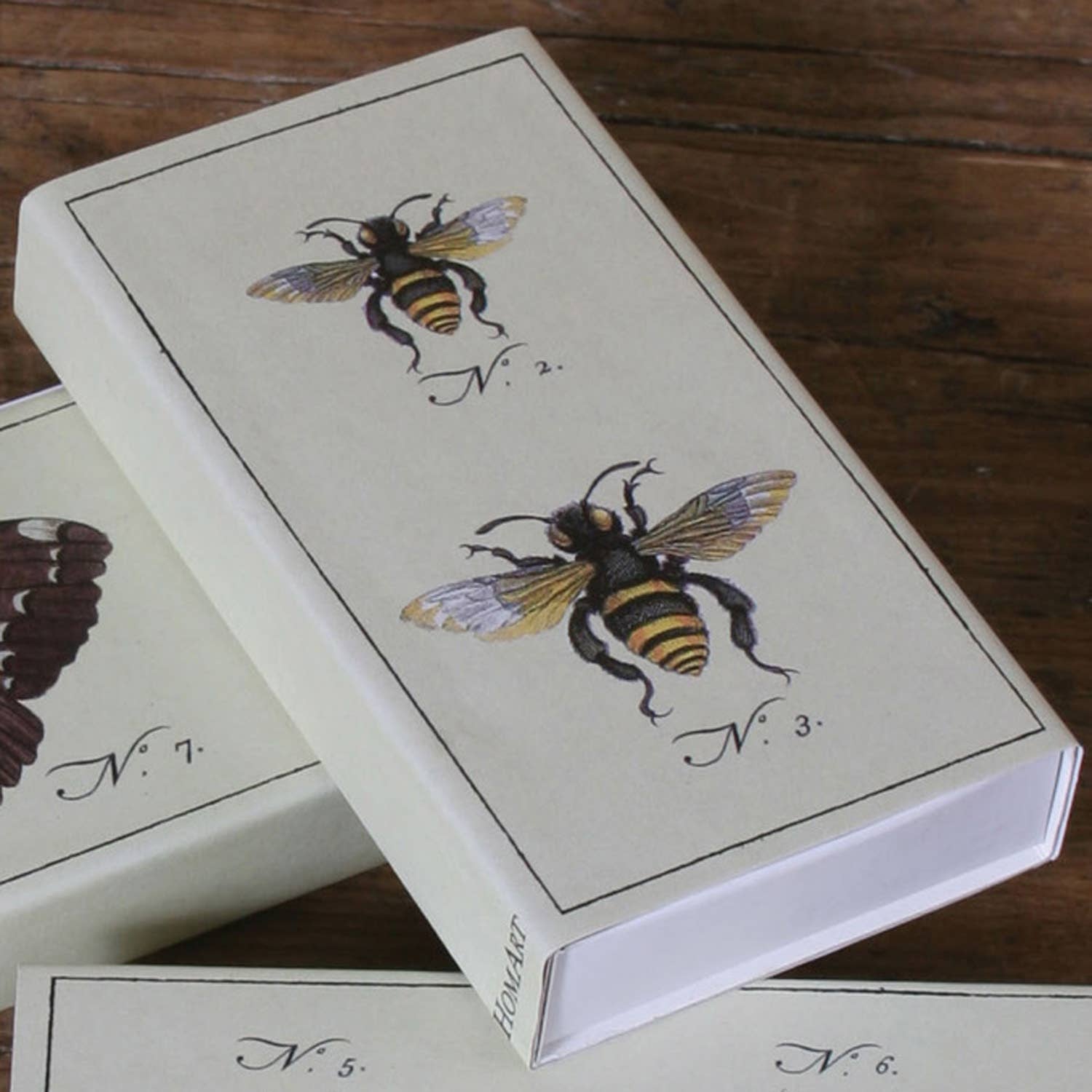 Playing card box with bee illustrations on a wooden surface
